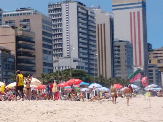 A group of people on a beach with a city in the background

Description automatically generated