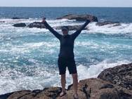 A person standing on a rocky beach next to the ocean

Description automatically generated